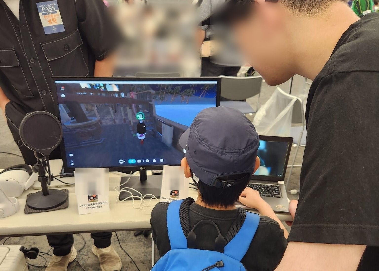 イベントブースで、モニターの画面を一緒に見る子どもとスタッフ